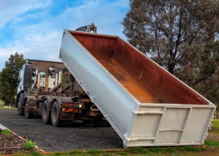 truck delivering a rubbish skip bin to building site
